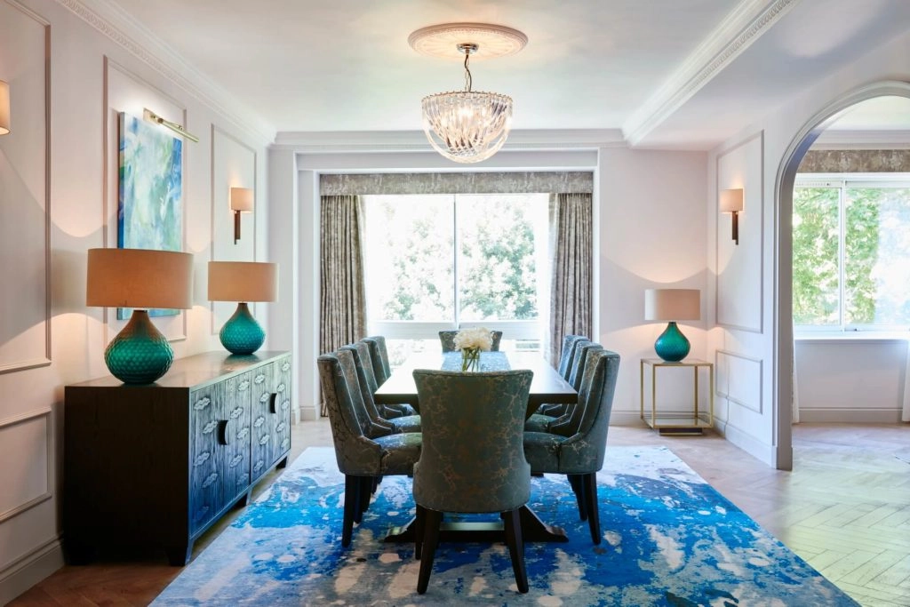 Elegant dining room at Arlington House Apartments with plush chairs, chandelier, and vibrant art, offering a stylish experience.