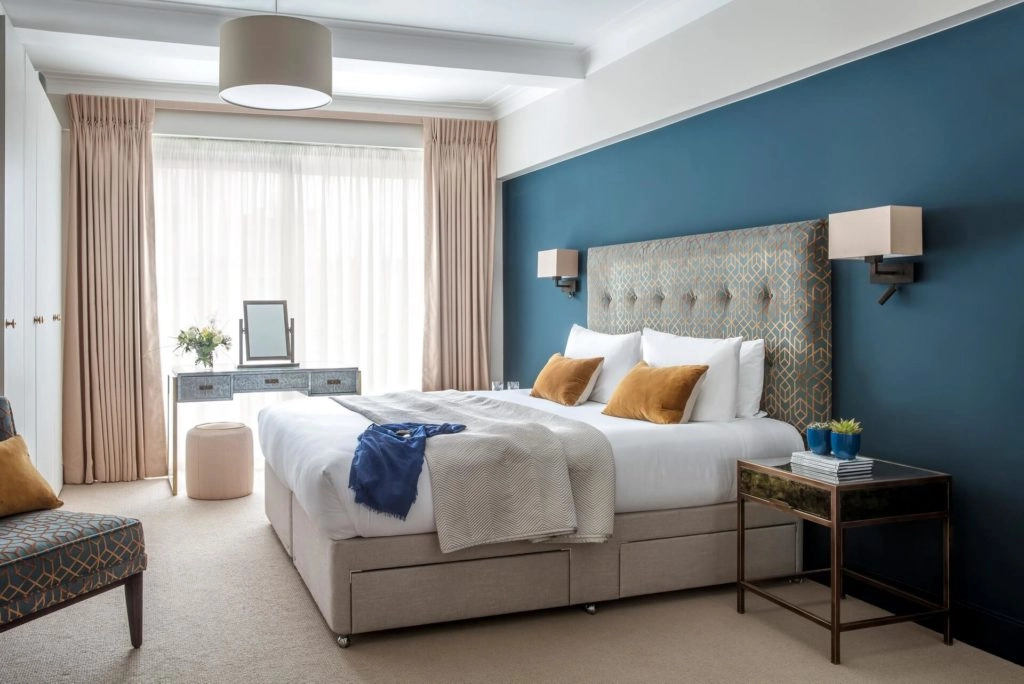 Elegant room with a plush double bed, stylish headboard, cosy seating, large windows, and modern decor at Arlington House.