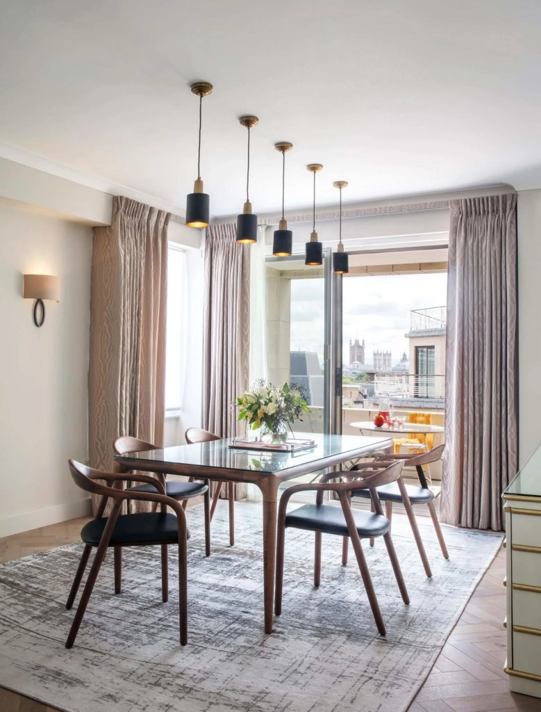 Elegant dining area with modern table, chic pendant lighting, large windows, and city view at Arlington House Apartments.