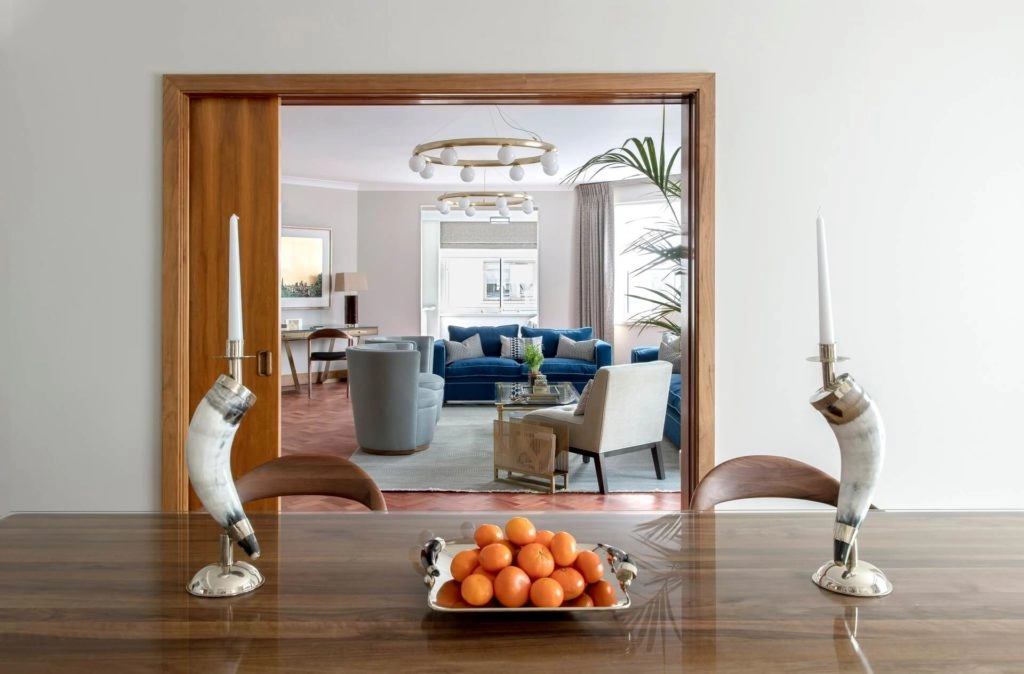 Elegant dining and living area with stylish decor, plush blue sofa, and a fruit platter, offering luxury and comfort in London.