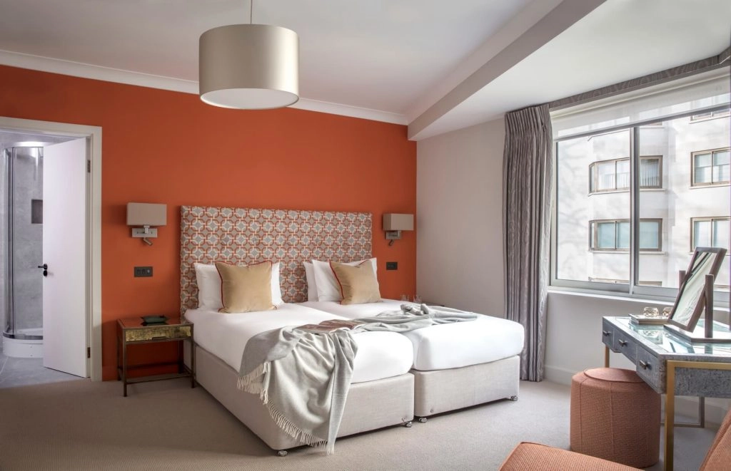 Elegant twin room with modern decor, cosy bedding, large window view, and ensuite at Arlington House Apartments.