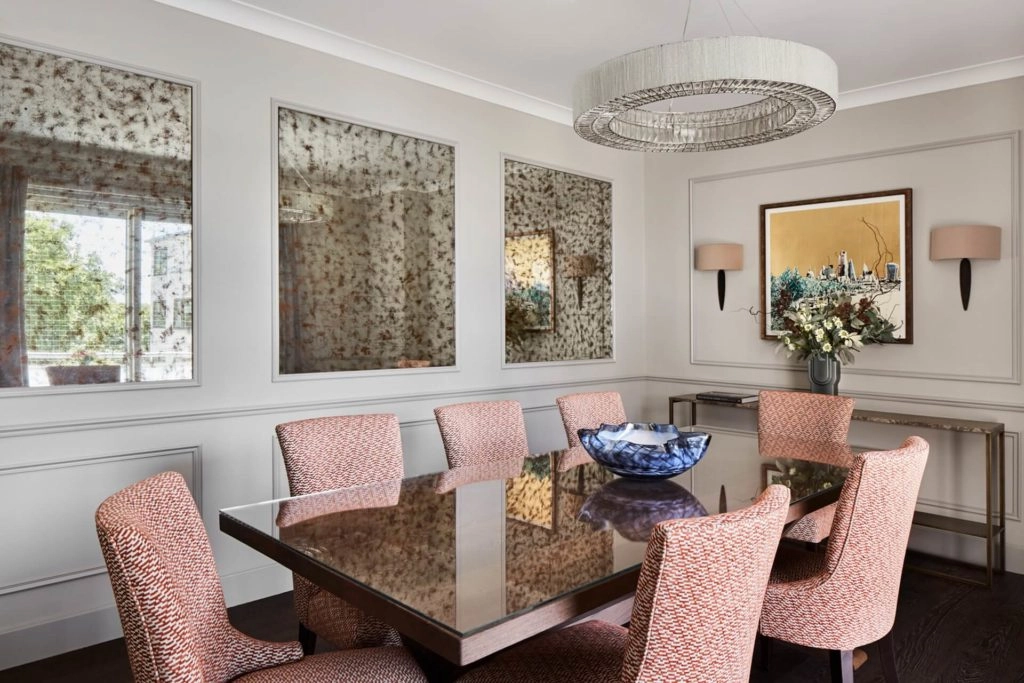 Elegant dining room with plush chairs, modern chandelier, art, and natural light at Arlington House Apartments.