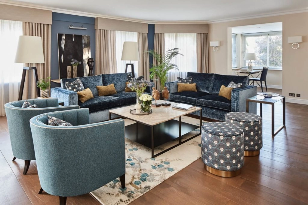 Elegant living area in Arlington House Apartments with plush seating, chic decor, and natural light from large windows.