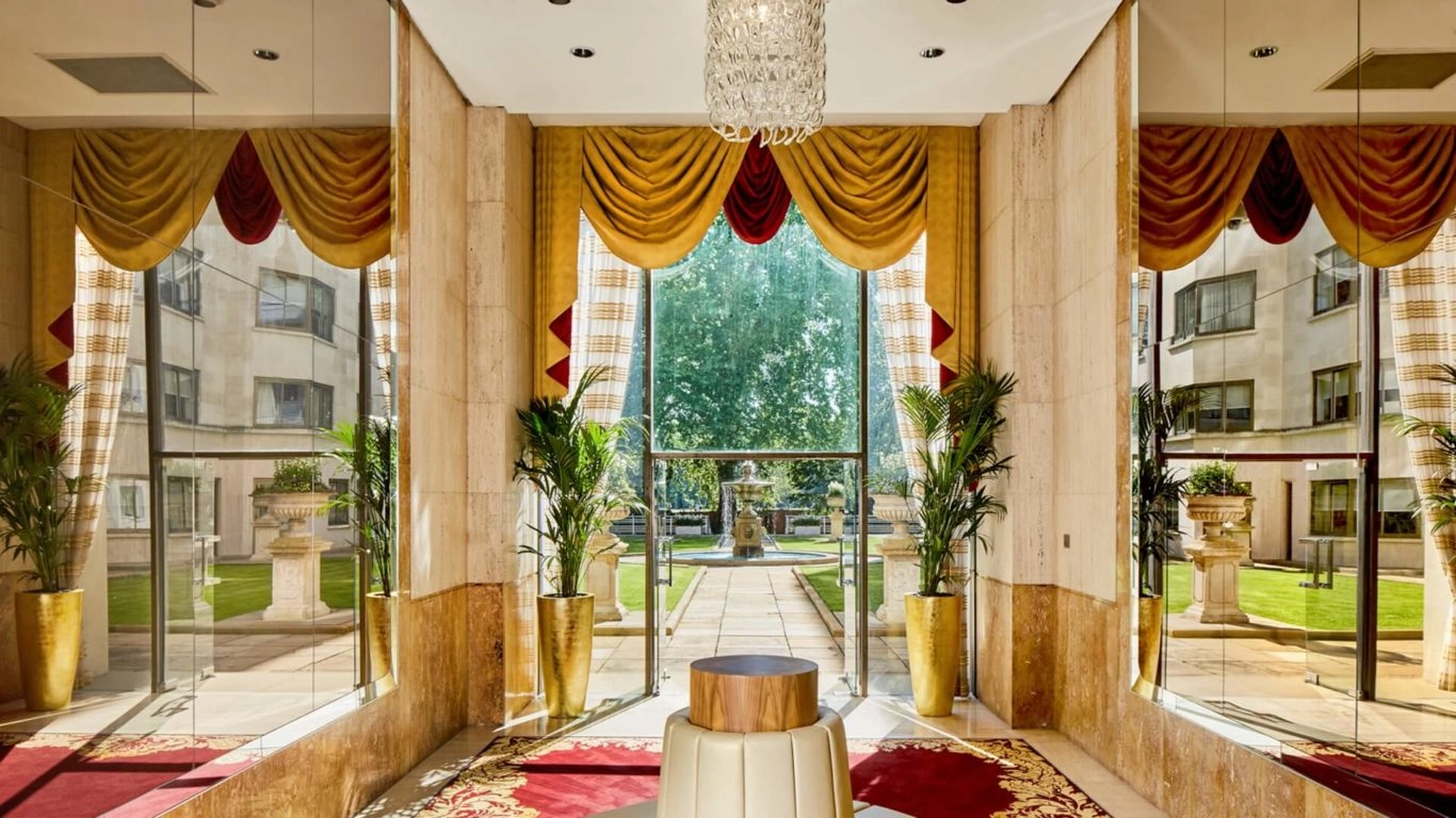 Luxurious hotel lobby with grand chandelier, elegant red carpet, and lush garden view at Arlington House Apartments.
