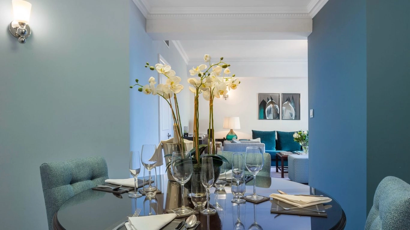 Elegant dining area with orchids, cosy seating, plush cushions, enhancing a warm, luxurious hotel stay in central London.