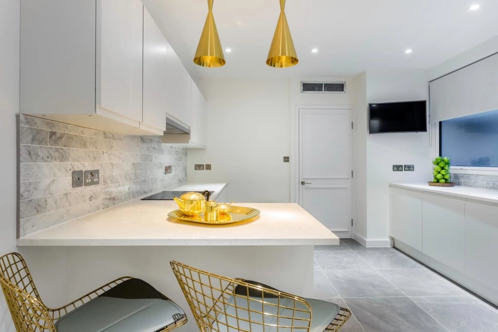 Enjoy elegant, modern kitchen amenities with gold accents, marble tiles, and stylish seating at Arlington House Apartments.