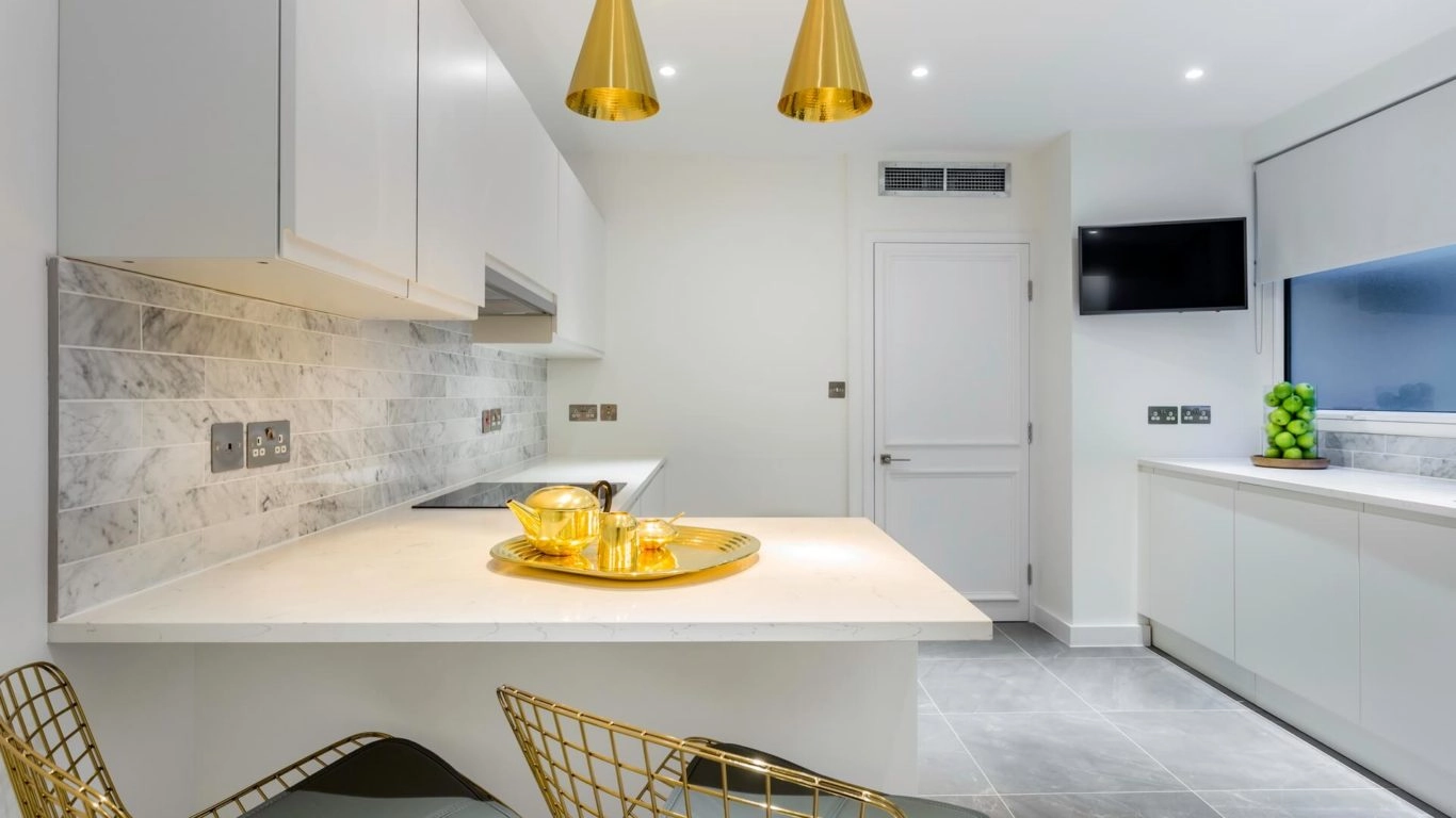 Enjoy elegant, modern kitchen amenities with gold accents, marble tiles, and stylish seating at Arlington House Apartments.
