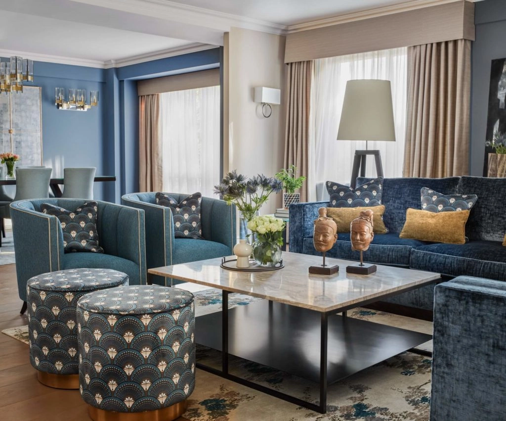 Elegant living area with plush blue sofas, artistic decor, and a cosy ambience at Arlington House Apartments.
