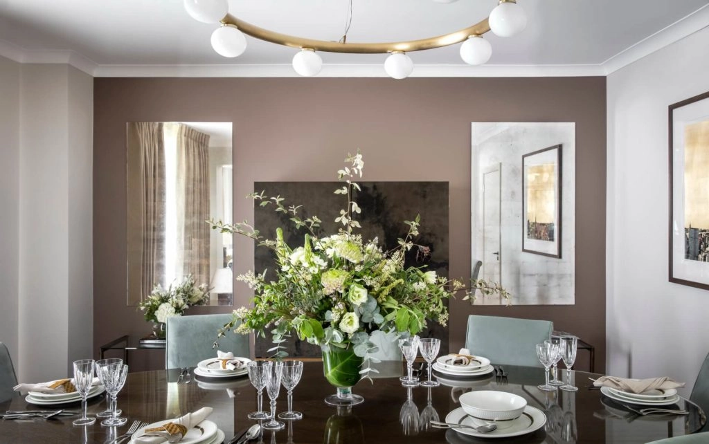 Elegant dining room with a polished wood table, stylish chandelier, and fresh floral centrepiece at Arlington House Apartments.