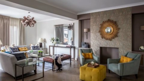 Elegant living room with plush sofas, modern decor, vibrant cushions, and natural light at Arlington House Apartments.