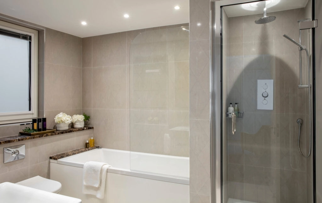 Modern bathroom with sleek shower, luxurious bathtub, floral accents, and elegant toiletries in Arlington House Apartments.