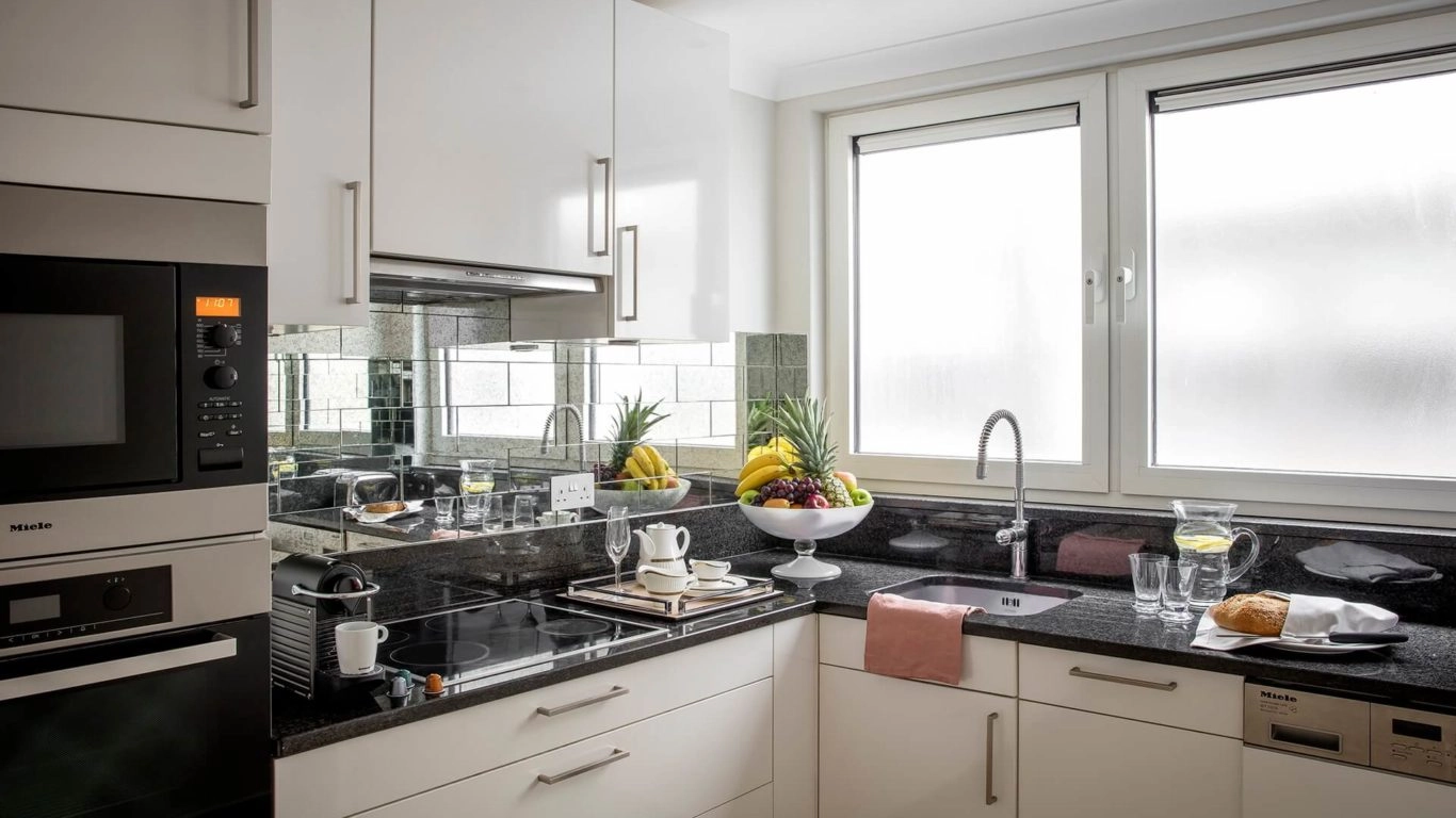 Modern kitchen with sleek appliances, fruit bowl, and dining set; inviting and well-equipped space in Arlington House Apartments.