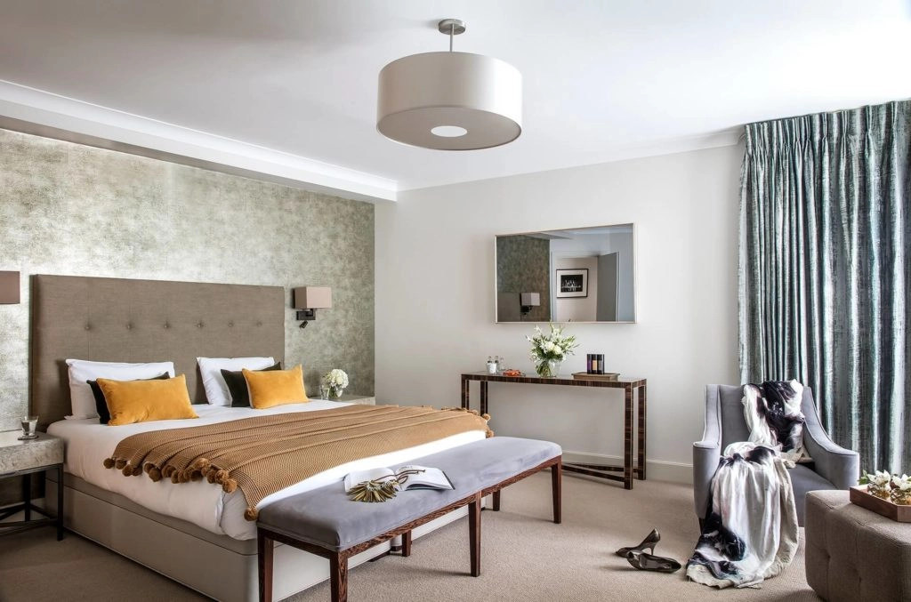 Elegant hotel room with king bed, cosy seating, chic decor, and natural light at Arlington House Apartments, London.
