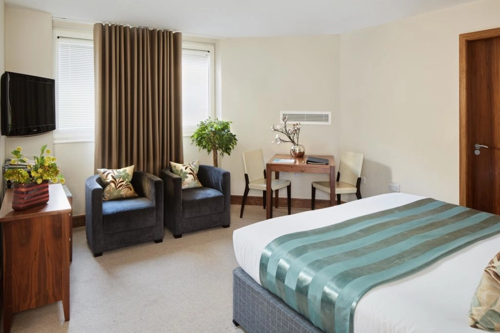 Elegant Arlington room with cosy chairs, stylish decor, flat-screen TV, and work desk. Perfect blend of comfort and luxury.