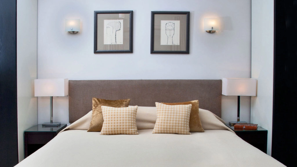 Elegant bedroom with plush pillows, modern lamps, and framed artwork at Arlington House Apartments, offering a cosy retreat.