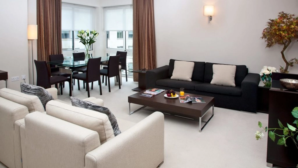 Spacious living area with cosy sofas, elegant dining table, and large windows at Arlington House Apartments, London.