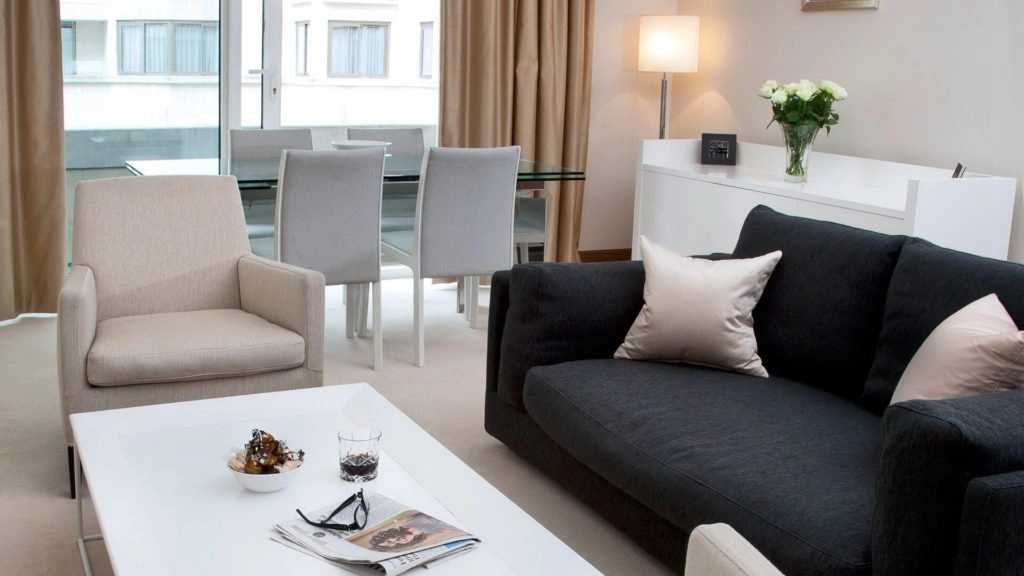 Luxurious Apartment Living Room Bright Arlington House Apartment lounge with comfortable sofas, elegant dining area, soft lighting, and fresh flowers.