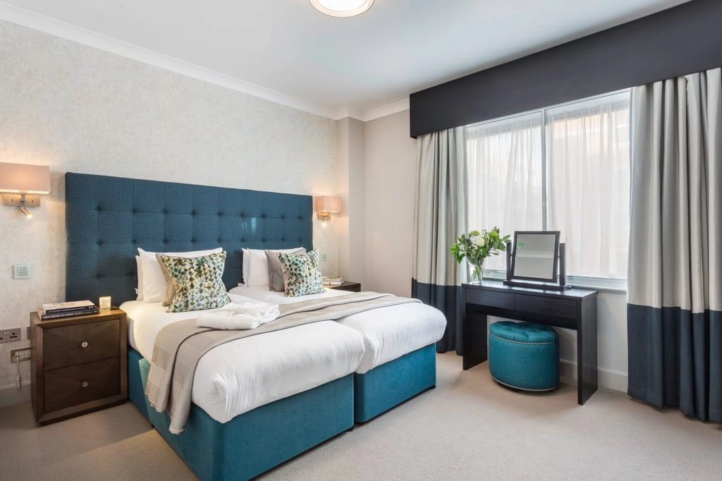 Elegant bedroom with plush double bed, stylish decor, natural light, and modern amenities at Arlington House Apartments.